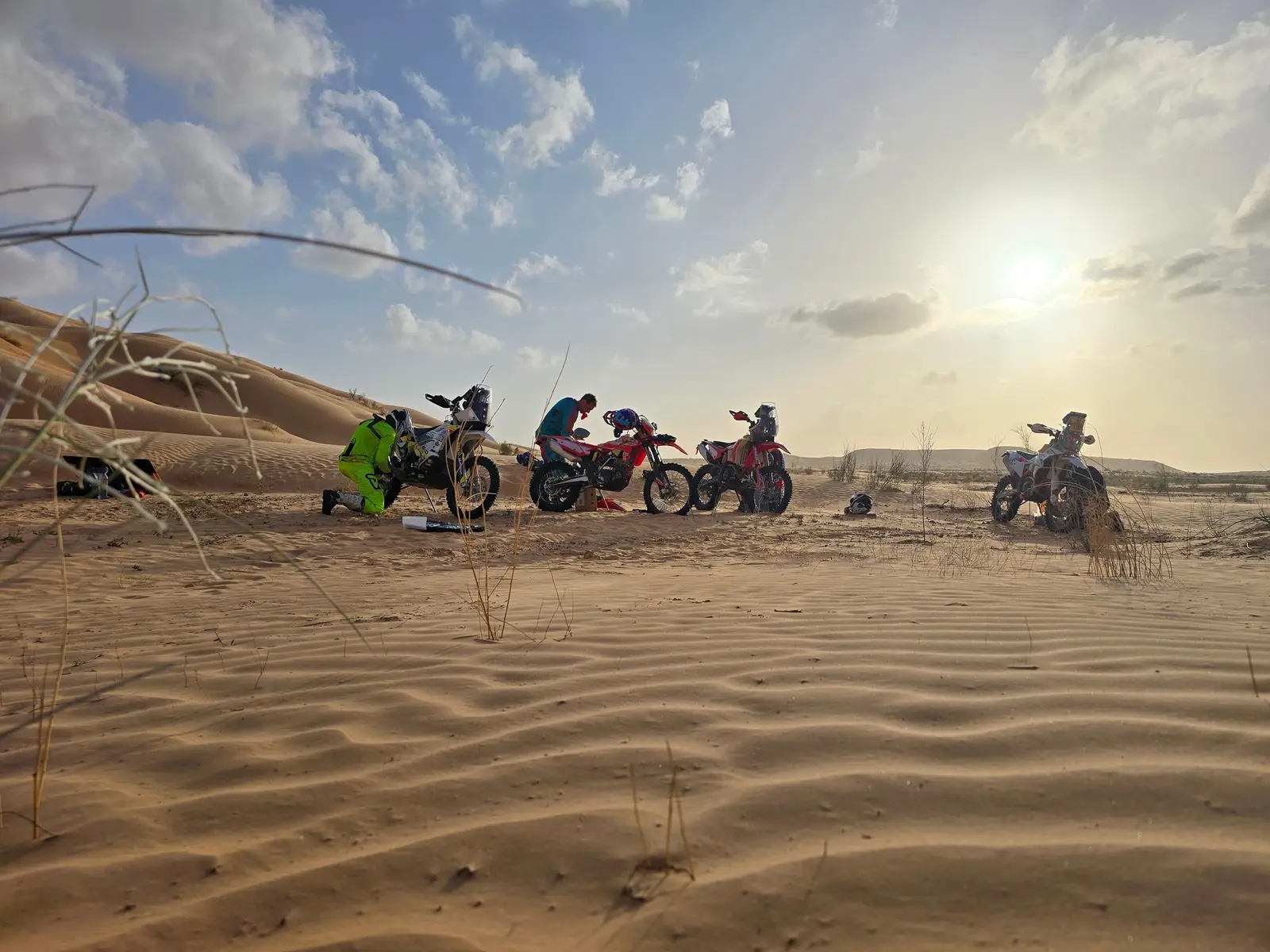 Vier Motorräder in den Dünen bei tiefstehender Sonne