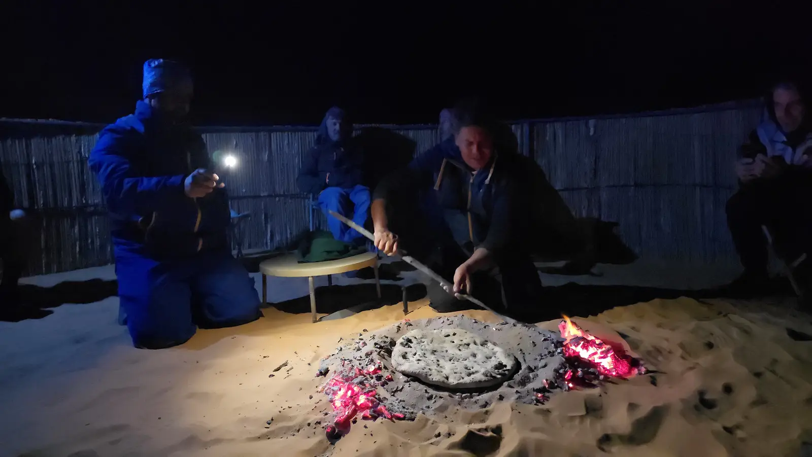 Das Serviceteam backt Fladenbrot in der Glut im Sand