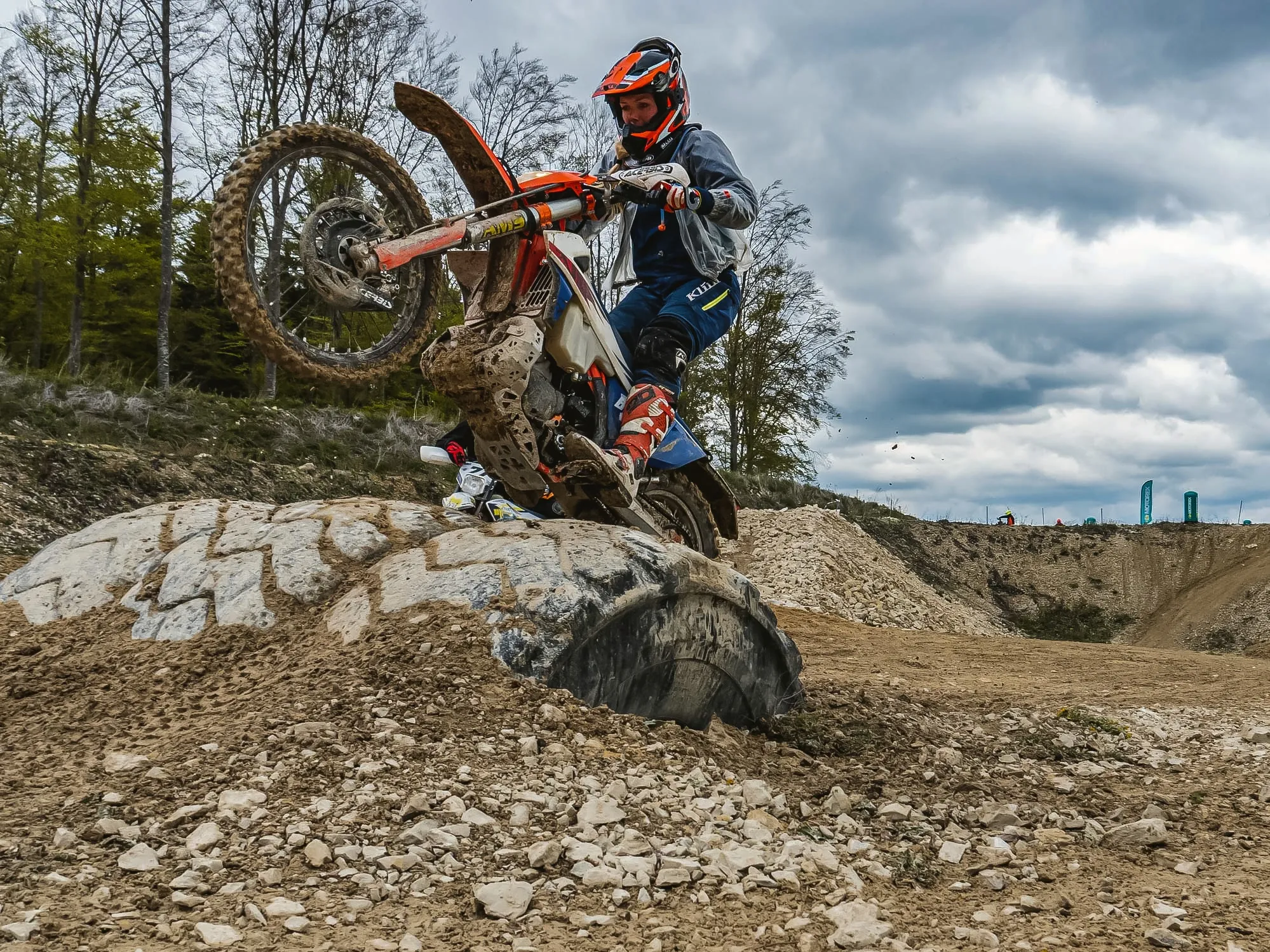 Enduro-Fahrerin mit Startnummer im Gelände, Vorderrad in der Luft