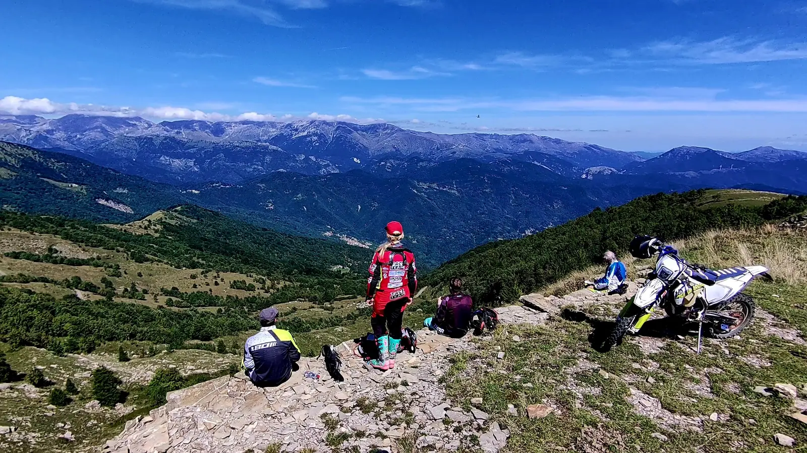 Pause auf einer Bergkuppe, dahinter das Alpenpanorama