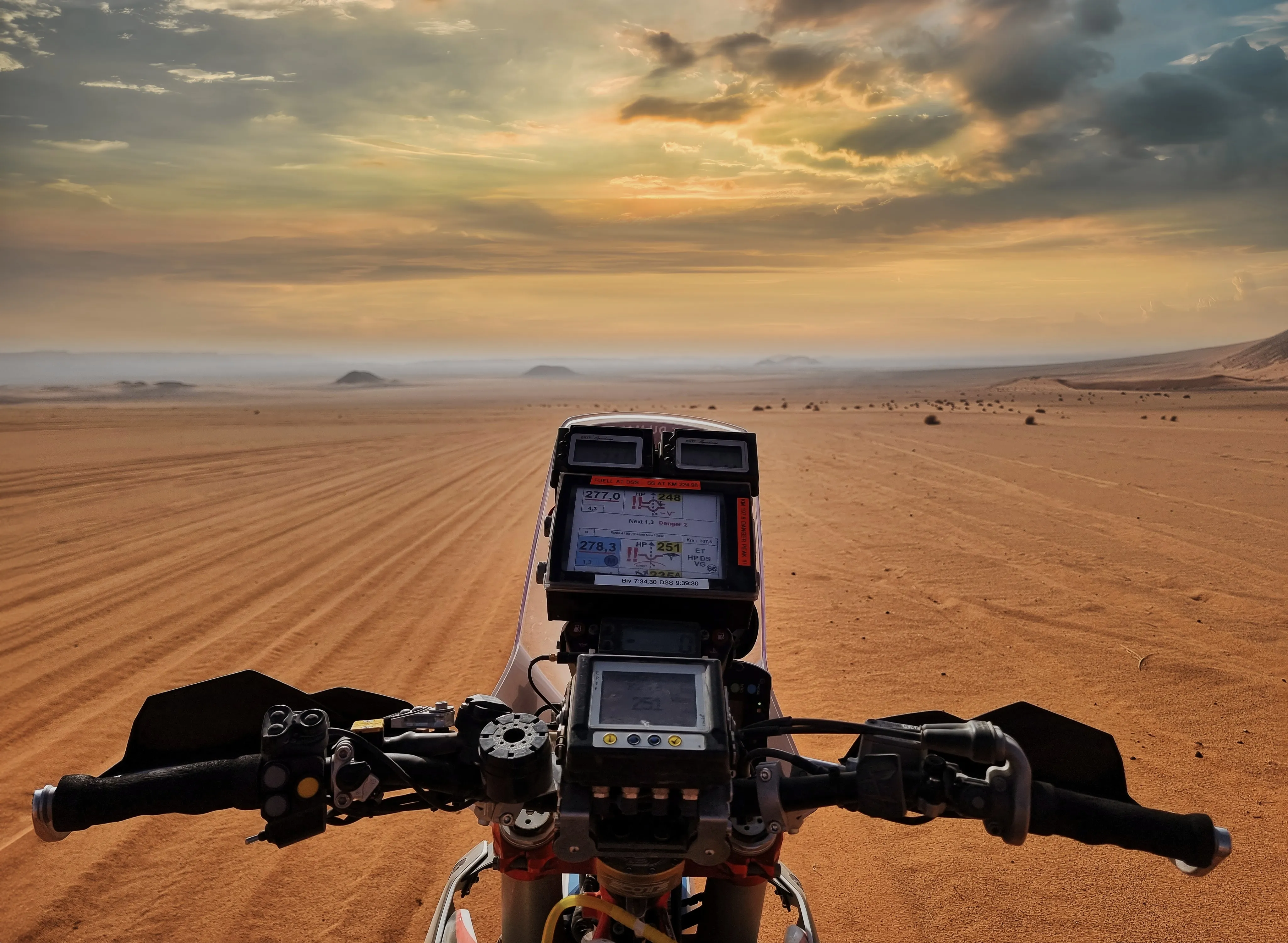 Blick über den Lenker auf Roadbook und Tripmaster, davor offene Wüste