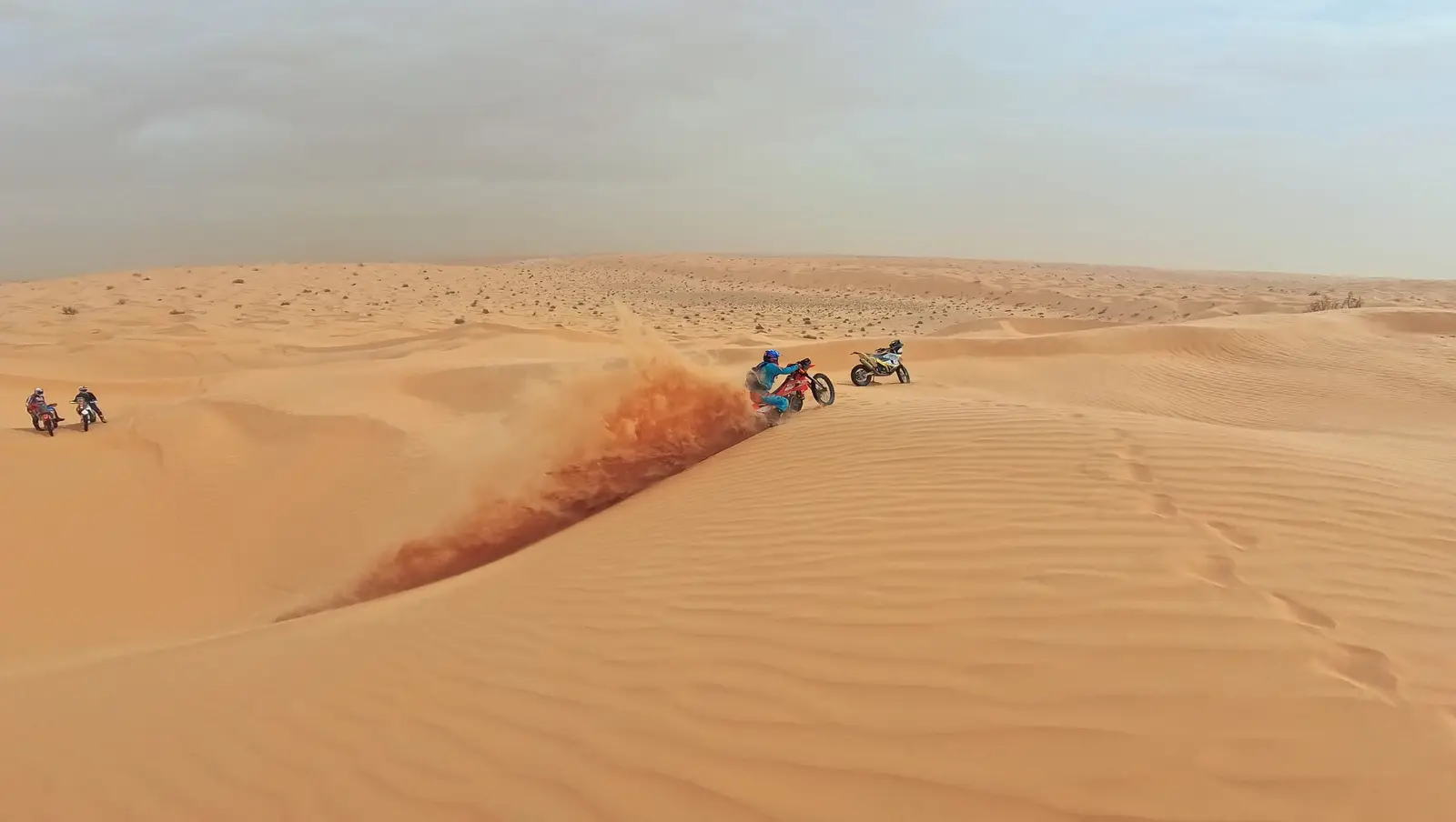 Zwei Motorräder auf einem Dünenkamm, dahinter eine Sandfahne